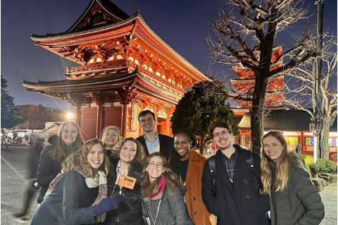 A group of Fletcher students poses with a Fletcher flag in front of Asakusa Shrine in Tokyo