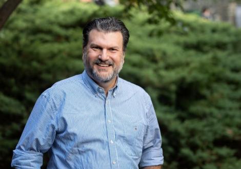 Dimitrios Skiadas smiles for a photo in front of blurry trees in the background.