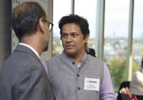Easwaran Narassimhan speaks with Alnoor Ebrahim inside of a room with sunny windows in the background.