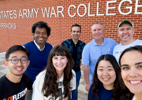 Fletcher's team at the Army War College Strategy Competition poses for a picture in front of a sign for the United States Army War College.