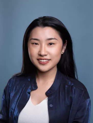 Sophie Hu smiles in front of a blue background. 