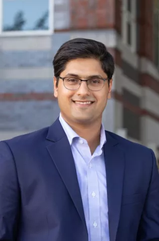 A headshot of Gautam Nair in front of a brick building