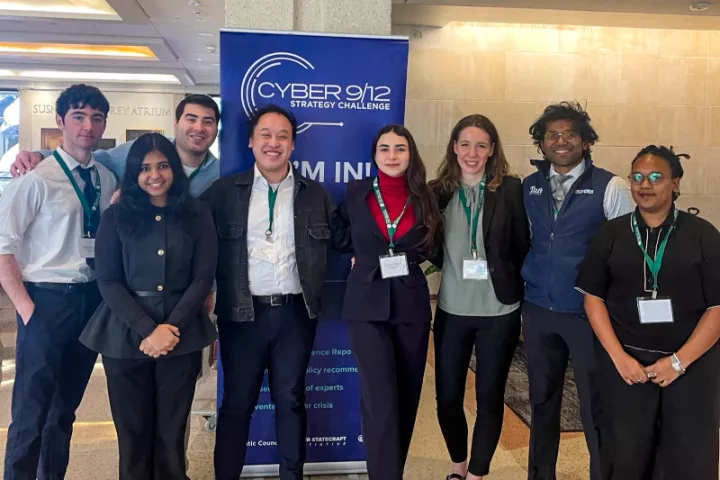 Fletcher students pose in front of a banner for Cyber 9/12