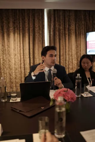 Armaan Mathur speaks into a microphone at a conference table.