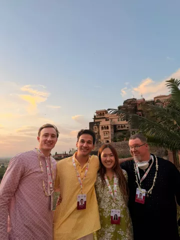 The four Fletcher NXT student fellows pose for a photo outside at sunset.