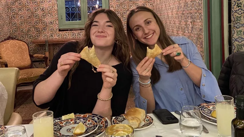 Two students enjoy a meal at an indoor restaurant.