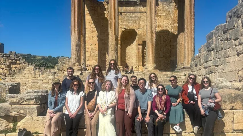 Fletcher students pose for a photo in front of an outdoor site in Tunisia. 