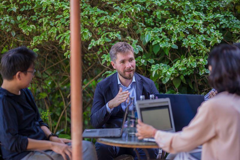 A group of GMAP students sits around a table outside, working and talking with each other. 