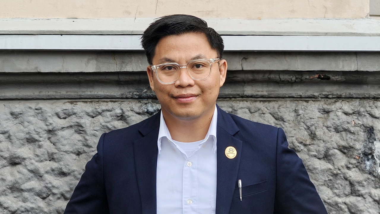 A headshot of Muhamad Aprisal standing in front of an exterior wall. 