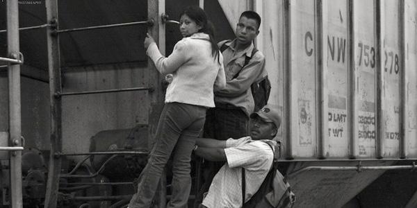 Migrants holding onto a railroad car