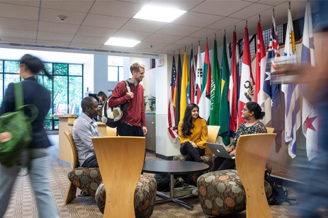 Students sitting at a table with world flags in the background