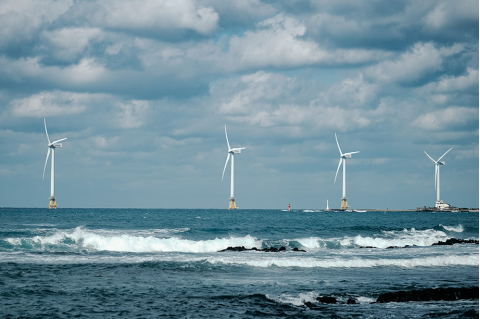 Wind turbines in the ocean with clouds in the sky