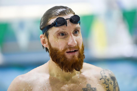 Brad Snyder, swim goggles on his head, stands in front of a swimming pool
