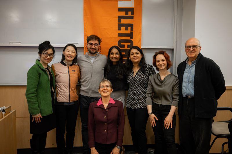 A group smiles in front of a Fletcher banner in the front of a classroom.