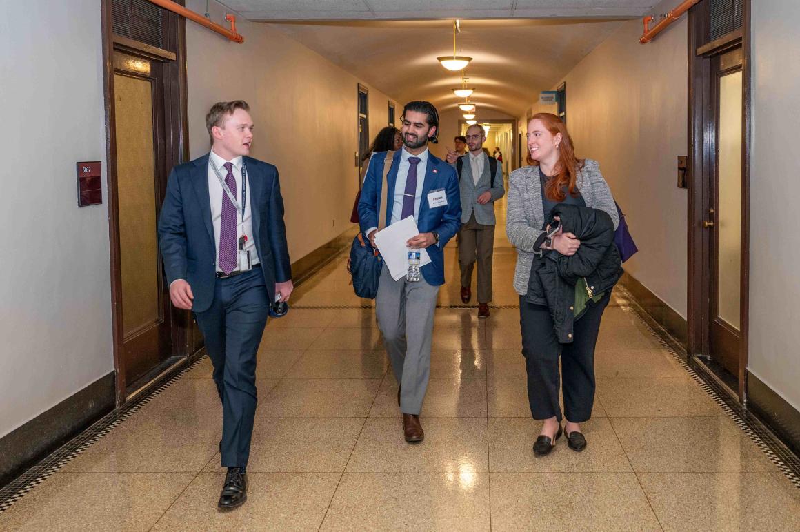 A diverse group of students and alumni walking in the hallway
