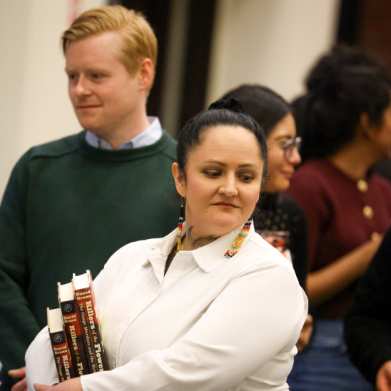 A student holds three copies of the book, Killers of the Flower Moon.