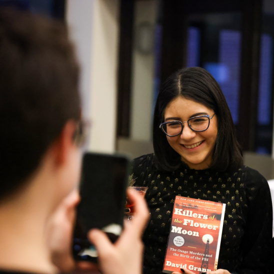 A student smiles while holding the book, Killers of the Flower Moon.