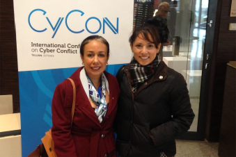Monica Ruiz and another person stand in front of a CyCon 2017 sign