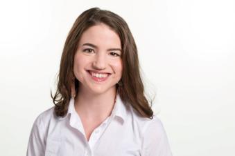 Elena Latzen smiles for a picture in front of a white background.