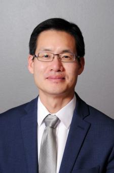 A headshot of Andrew Yeo in front of a gray background