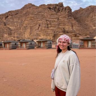 Kate Hibbert smiles for a picture in front of a mountain in the desert.