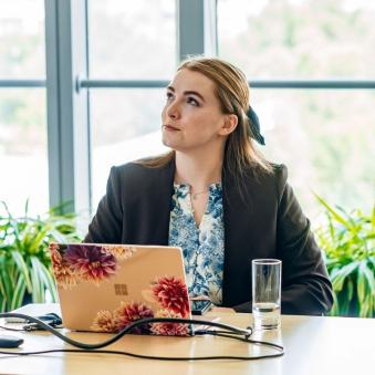 Katherine Walsh sits in front of a laptop while gazing into the distance.