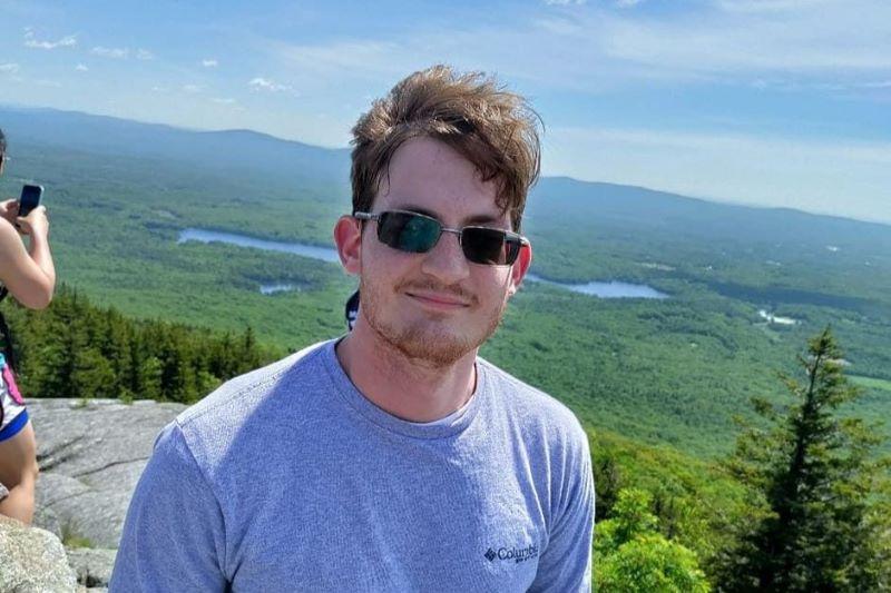 An outdoor headshot of Harrison Wedgeworth in front of a green background