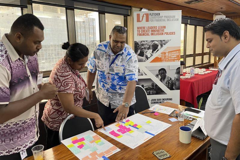 FLPFI participants stand around a table, looking at documents. 