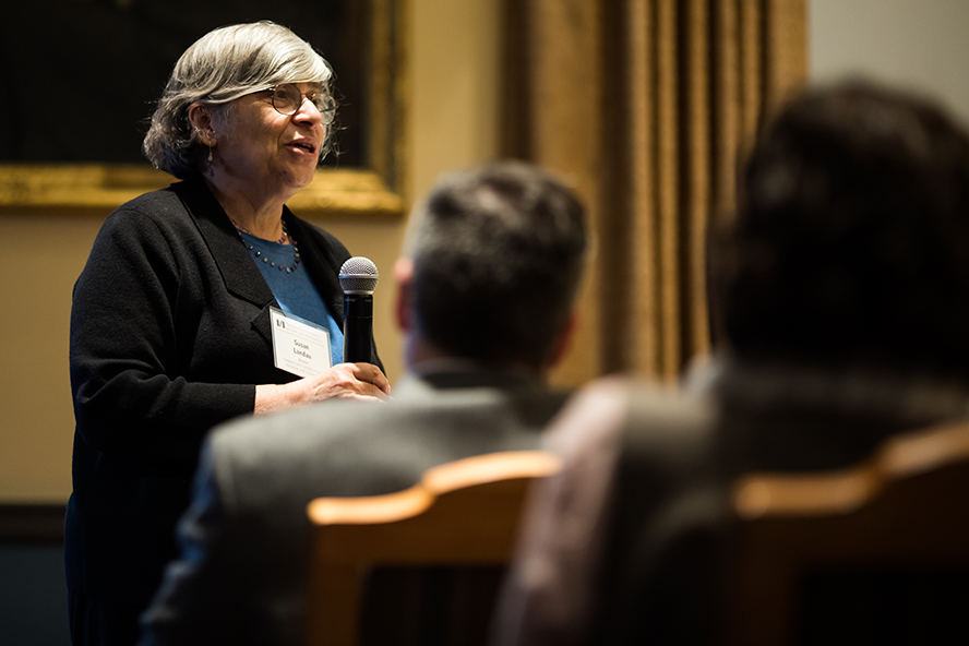 Susan Landau is holding a microphone and talking to a lecture hall