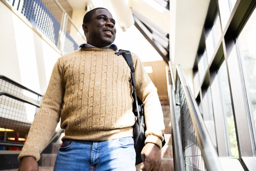 A man wearing a sweater walks down a well-lit staircase