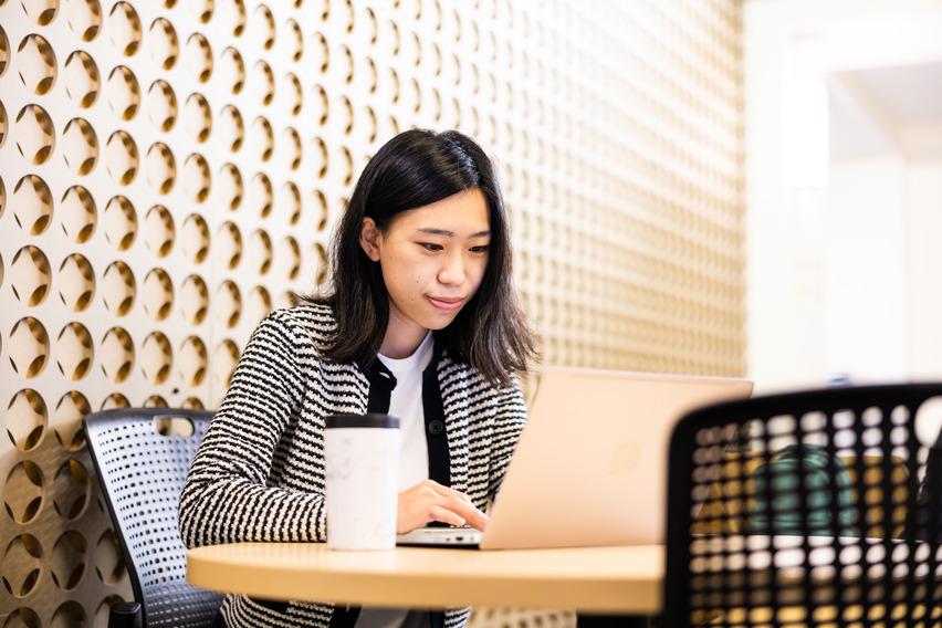 A woman in a white and black blazer looking at a laptop