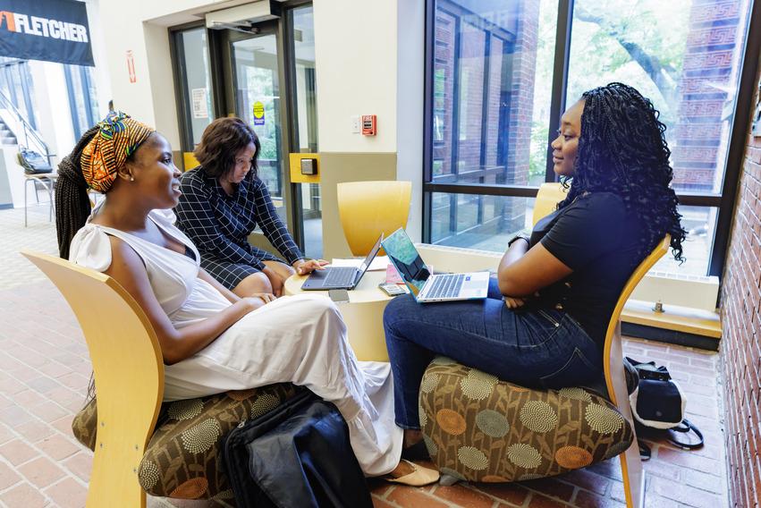 Three women are sitting in a circle. Two of them are looking at each other
