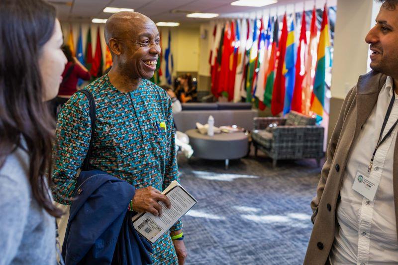 Chidi Odinkalu speaks with two students in the Hall of Flags.