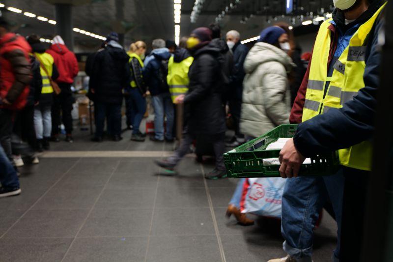 People in hi-vis vests provide distribute aid to refugees from Ukraine.