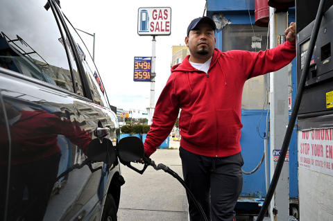 A man pumps gas into a car at a gas station.