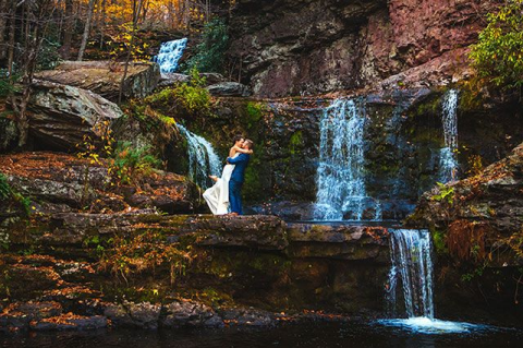 Bride and groom kissing in front of waterfalls
