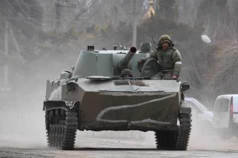A Russian tank with a soldier on top on a road in Crimea