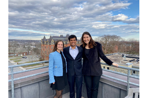 Fiona Negron, wearing a light blue jacket; Gaurav Redhal, wearing a blue suit and Sophia Warner, wearing a black suit on a balcony of the Cabot building