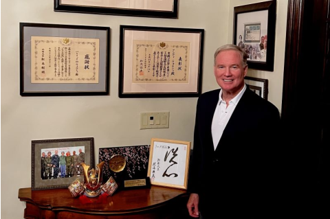 Admiral Walsh stands in front of awards and citations he has received from the Japanese government.