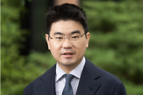 A headshot of Thomas Cao in front of a blurred, green background outdoors