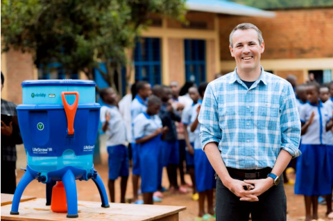 Evan Thomas stands, smiling, next to a Virridy clean water system.