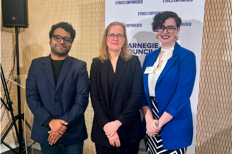 Vishal Manve, Monica Toft, and Samantha Hubner pose for a picture in front of a Carnegie Council banner.