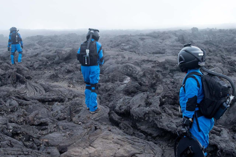 Simulation crew members walk on a solid bed of lava.