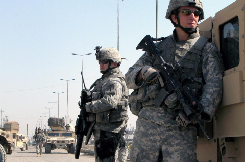 Two armed U.S. soldiers stand guard in Iraq.