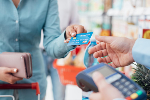 Woman at the supermarket checkout, she is paying using a credit card